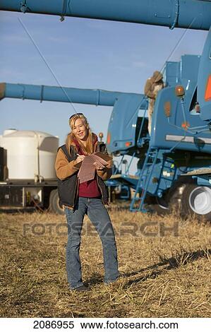 Woman documenting notes with farm equipment in the background; three hills alberta canada View Large Photo Image Stock Photography - Woman documenting notes with farm equipment in the background; three hills alberta canada. Fotosearch
