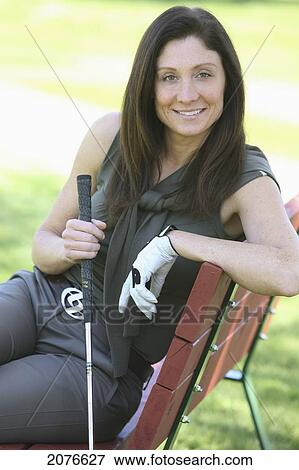 Woman sitting on a bench holding a golf club; troutdale oregon united states of america View Large Photo Image Stock Photo - Woman sitting on a bench holding a golf club; troutdale oregon united states of america. Fotosearch