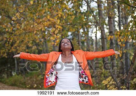 Stock Image - Woman Spreading Arms And Looking Upwards In A Park In Autumn; Edmonton Alberta Canada. Fotosearch