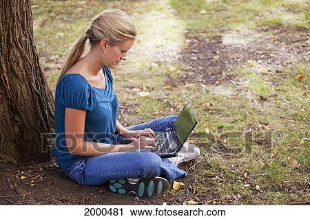 Stock Image - Woman Working On Netbook Computer In A Park; Edmonton Alberta Canada. Fotosearch