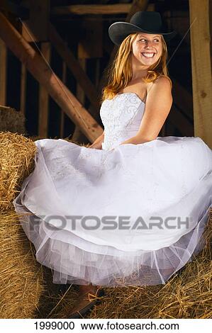 Stock Image - Young Bride In A Barn Wearing A Cowgirl Hat; Pennock Minnesota United States Of America. Fotosearch