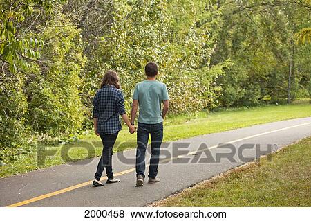 Young Couple Walking Down A Park Path; Edmonton Alberta Canada View Large Photo Image Stock Photo - Young Couple Walking Down A Park Path; Edmonton Alberta Canada. Fotosearch