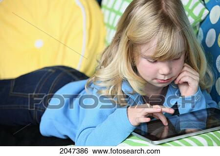 Young Girl Laying On A Couch Playing With An Electronic Notebook; Troutdale Oregon United States Of America View Large Photo Image Stock Photograph - Young Girl Laying On A Couch Playing With An Electronic Notebook; Troutdale Oregon United States Of America. Fotosearch