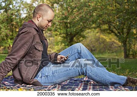 Young Man Texting In The Park; Edmonton Alberta Canada View Large Photo Image Stock Photography - Young Man Texting In The Park; Edmonton Alberta Canada. Fotosearch