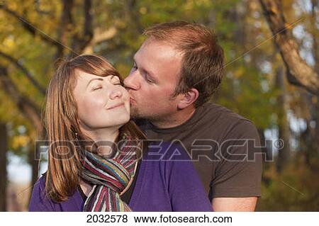 Stock Photo - Young Married Couple Embracing And Kissing In A Park; Edmonton Alberta Canada. Fotosearch