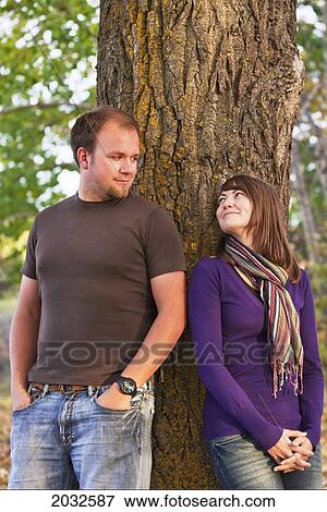 Stock Photo - Young Married Couple Leaning Against A Tree In A Park In Autumn; Edmonton Alberta Canada. Fotosearch