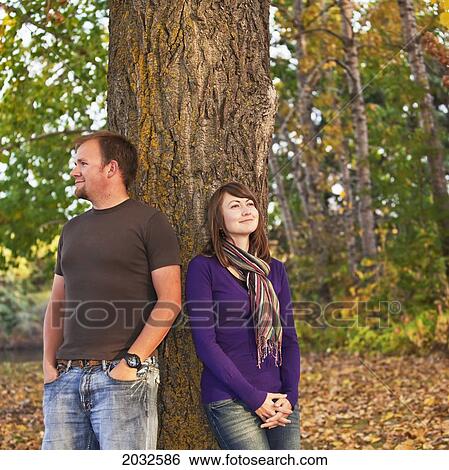 Young Married Couple Leaning Against A Tree In A Park In Autumn; Edmonton Alberta Canada View Large Photo Image Stock Photograph - Young Married Couple Leaning Against A Tree In A Park In Autumn; Edmonton Alberta Canada. Fotosearch