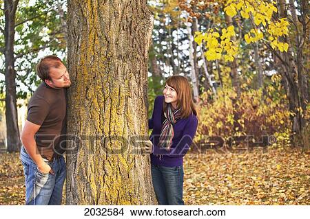 Young Married Couple Peaking At Each Other Around A Tree In A Park In Autumn; Edmonton Alberta Canada View Large Photo Image Picture - Young Married Couple Peaking At Each Other Around A Tree In A Park In Autumn; Edmonton Alberta Canada. Fotosearch