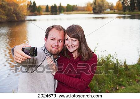 Young Married Couple Taking A Picture Of Themselves In A Park In Autumn; Edmonton Alberta Canada View Large Photo Image Stock Photo - Young Married Couple Taking A Picture Of Themselves In A Park In Autumn; Edmonton Alberta Canada. Fotosearch