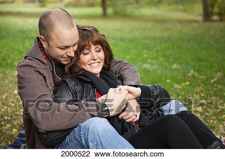 Stock Image - Young Newlywed Coup; Le In A Park Together Looking At Her Wedding Ring; Edmonton Alberta Canada. Fotosearch