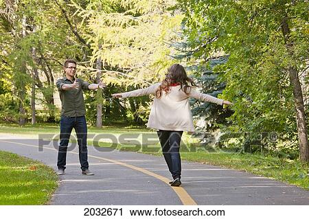 Stock Image - Young Wife 'walking The Line' Towards Husband On A Path In A Park; Edmonton Alberta Canada. Fotosearch