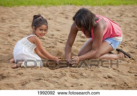 Stock Image - Young Woman Playing In The Sand With A Toddler; Edmonton Alberta Canada. Fotosearch