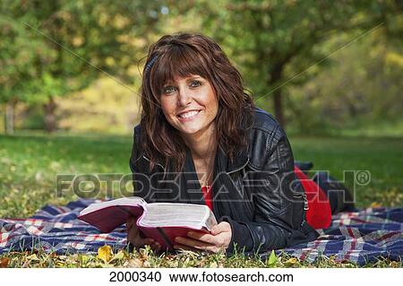 Stock Image - Young Woman Reading The Bible And Meditating In A Park; Edmonton Alberta Canada. Fotosearch