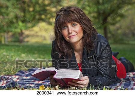 Stock Image - Young Woman Reading The Bible And Meditating In A Park; Edmonton Alberta Canada. Fotosearch