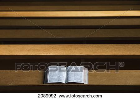 Stock Image - A bible open on a wooden bench; northumberland, england. Fotosearch
