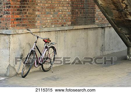 Stock Photography - A bicycle parked beside a brick wall; beijing china. Fotosearch