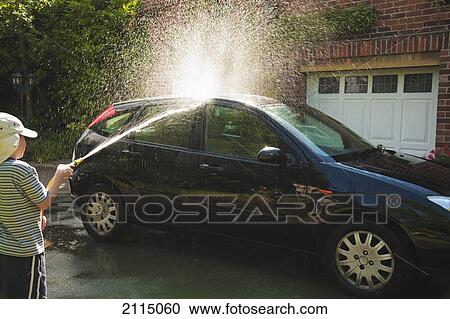 Stock Image - A boy washes a car in the driveway; england. Fotosearch