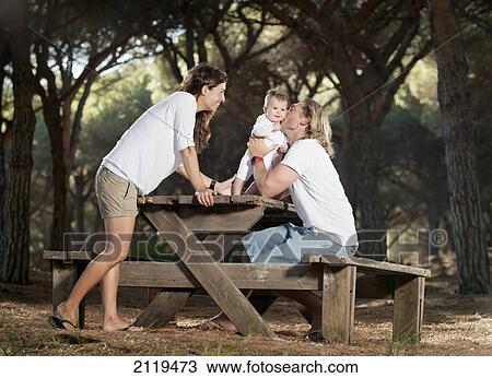 Stock Image - A family with a baby at a picnic table; tarifa cadiz andalusia spain. Fotosearch