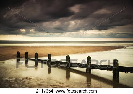 A fence submerged in the water at the coast with storm clouds overhead; berwick northumberland england View Large Photo Image Picture - A fence submerged in the water at the coast with storm clouds overhead; berwick northumberland england. Fotosearch