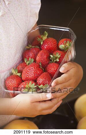 Stock Photo - A girl holding a basket of strawberries; torremolinos, malaga, spain. Fotosearch