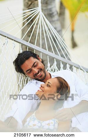 Stock Photo - A man and woman in a hammock at the bora bora nui resort and spa; bora bora island society islands french polynesia south pacific. Fotosearch