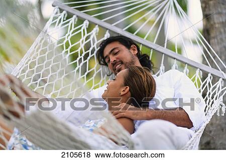 Stock Photo - A man and woman in a hammock at the bora bora nui resort and spa; bora bora island society islands french polynesia south pacific. Fotosearch