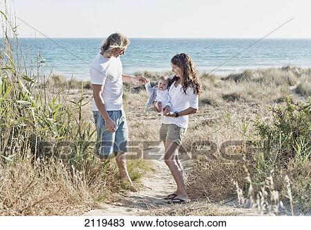 Stock Image - A mother and father with infant at the beach; tarifa cadiz andalusia spain. Fotosearch