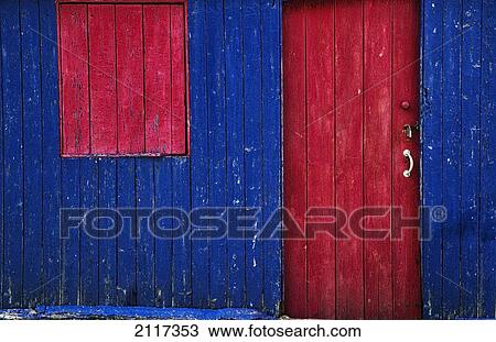 Stock Image - A painted red door and window cover on a blue wooden building; st abb's head scottish borders scotland. Fotosearch