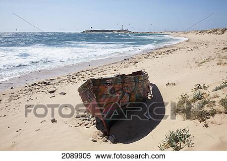 A painted wooden canoe sitting on a beach with the cape trafalgar lighthouse in the background; andalusia, spain View Large Photo Image Stock Photography - A painted wooden canoe sitting on a beach with the cape trafalgar lighthouse in the background; andalusia, spain. Fotosearch