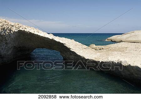 Stock Photo - A tranquil pool of water and unique rock formation off the coast; karpos, island of milos, greece. Fotosearch