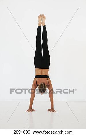 Stock Photo - A woman doing a handstand on a white background; tarifa, cadiz, andalusia, spain. Fotosearch