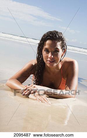 A woman in a bikini lays on the sand of a beach at low tide; gold coast queensland australia View Large Photo Image Stock Photo - A woman in a bikini lays on the sand of a beach at low tide; gold coast queensland australia. Fotosearch