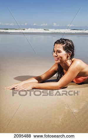 A woman in a bikini lays on the sand of a beach at low tide; gold coast queensland australia View Large Photo Image Stock Photo - A woman in a bikini lays on the sand of a beach at low tide; gold coast queensland australia. Fotosearch