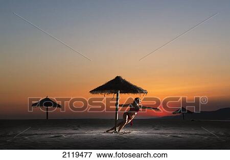 A woman in a bikini on the beach under an umbrella at sunset; tarifa cadiz andalusia spain View Large Photo Image Stock Photo - A woman in a bikini on the beach under an umbrella at sunset; tarifa cadiz andalusia spain. Fotosearch