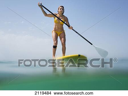 A woman in a yellow bikini paddles on a yellow board; tarifa cadiz andalusia spain View Large Photo Image Picture - A woman in a yellow bikini paddles on a yellow board; tarifa cadiz andalusia spain. Fotosearch