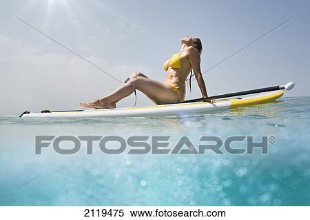 A woman in a yellow bikini sits with her paddle and board basking in the sunlight on the ocean; tarifa cadiz andalusia spain View Large Photo Image Stock Photography - A woman in a yellow bikini sits with her paddle and board basking in the sunlight on the ocean; tarifa cadiz andalusia spain. Fotosearch