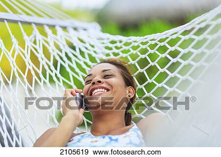 A woman lays in a hammock talking on a cell phone at the bora bora nui resort and spa; bora bora island society islands french polynesia south pacific View Large Photo Image Stock Photo - A woman lays in a hammock talking on a cell phone at the bora bora nui resort and spa; bora bora island society islands french polynesia south pacific. Fotosearch