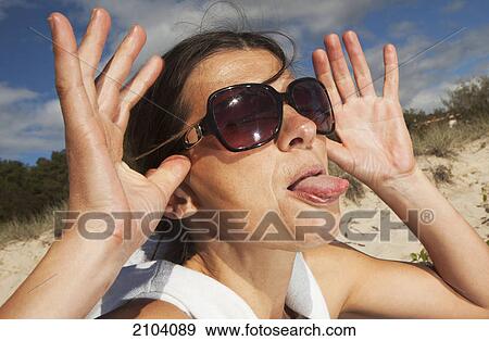 Stock Photo - A woman makes a funny face with her tongue sticking out at the beach; gold coast queensland australia. Fotosearch