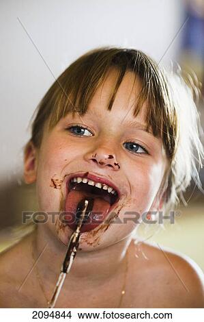 A young girl eating a chocolate treat on a stick with a messy face; gold coast queensland australia View Large Photo Image Picture - A young girl eating a chocolate treat on a stick with a messy face; gold coast queensland australia. Fotosearch