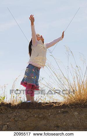 A young girl joyfully raising her arms towards the sky; fuengirola malaga province spain View Large Photo Image Stock Photo - A young girl joyfully raising her arms towards the sky; fuengirola malaga province spain. Fotosearch