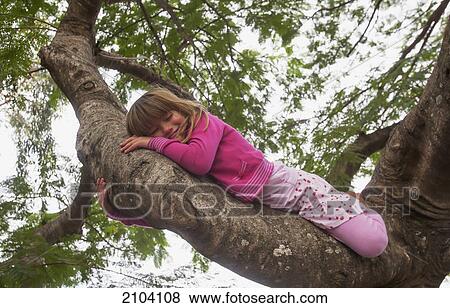 Stock Photo - A young girl laying on a tree branch; gold coast queensland australia. Fotosearch