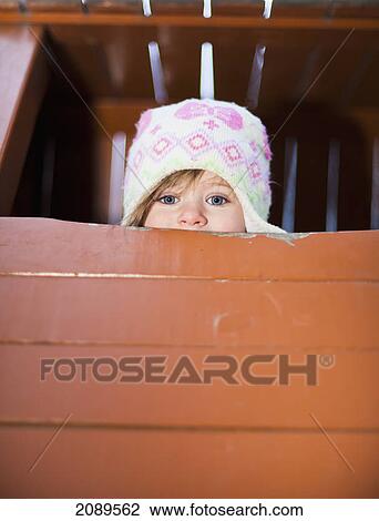 A young girl peeks over edge of playground equipment; beijing, china View Large Photo Image Stock Image - A young girl peeks over edge of playground equipment; beijing, china. Fotosearch