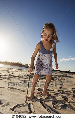 Stock Image - A young girl playing in the sand at the beach; gold coast queensland australia. Fotosearch