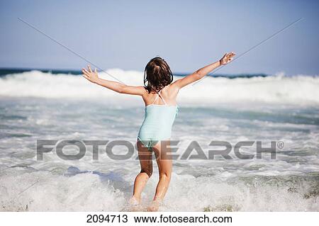 Stock Image - A young girl plays in the waves of the ocean; gold coast, queensland, australia. Fotosearch