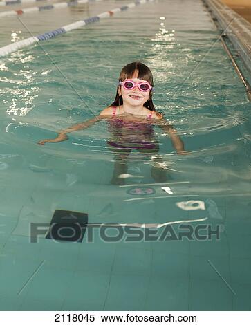 Stock Photography - A young girl wearing pink goggles in a swimming pool; gold coast queensland australia. Fotosearch