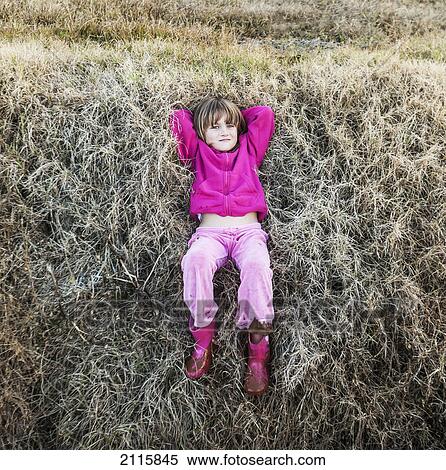 Stock Photography - A young girl wearing pink laying on the grass; queensland gold coast australia. Fotosearch