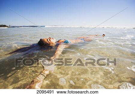 A young woman lays in the shallow water off the beach; gold coast queensland australia View Large Photo Image Stock Image - A young woman lays in the shallow water off the beach; gold coast queensland australia. Fotosearch