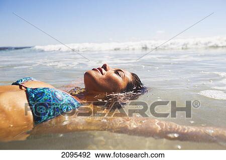A young woman lays in the shallow water off the beach; gold coast queensland australia View Large Photo Image Stock Image - A young woman lays in the shallow water off the beach; gold coast queensland australia. Fotosearch