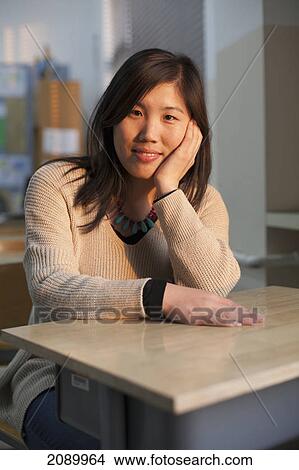 A young woman sits at a desk in a classroom; beijing, china View Large Photo Image Picture - A young woman sits at a desk in a classroom; beijing, china. Fotosearch