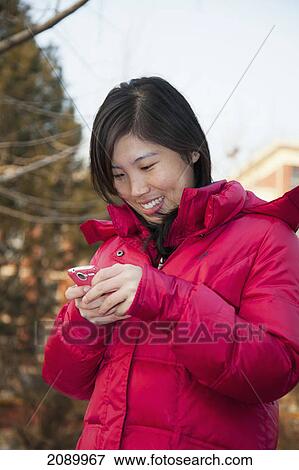A young woman using her cell phone; beijing, china View Large Photo Image Stock Photo - A young woman using her cell phone; beijing, china. Fotosearch